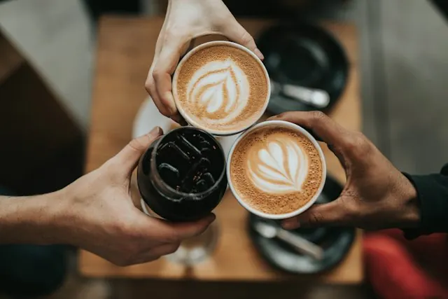 Three hands toasting with latte cups